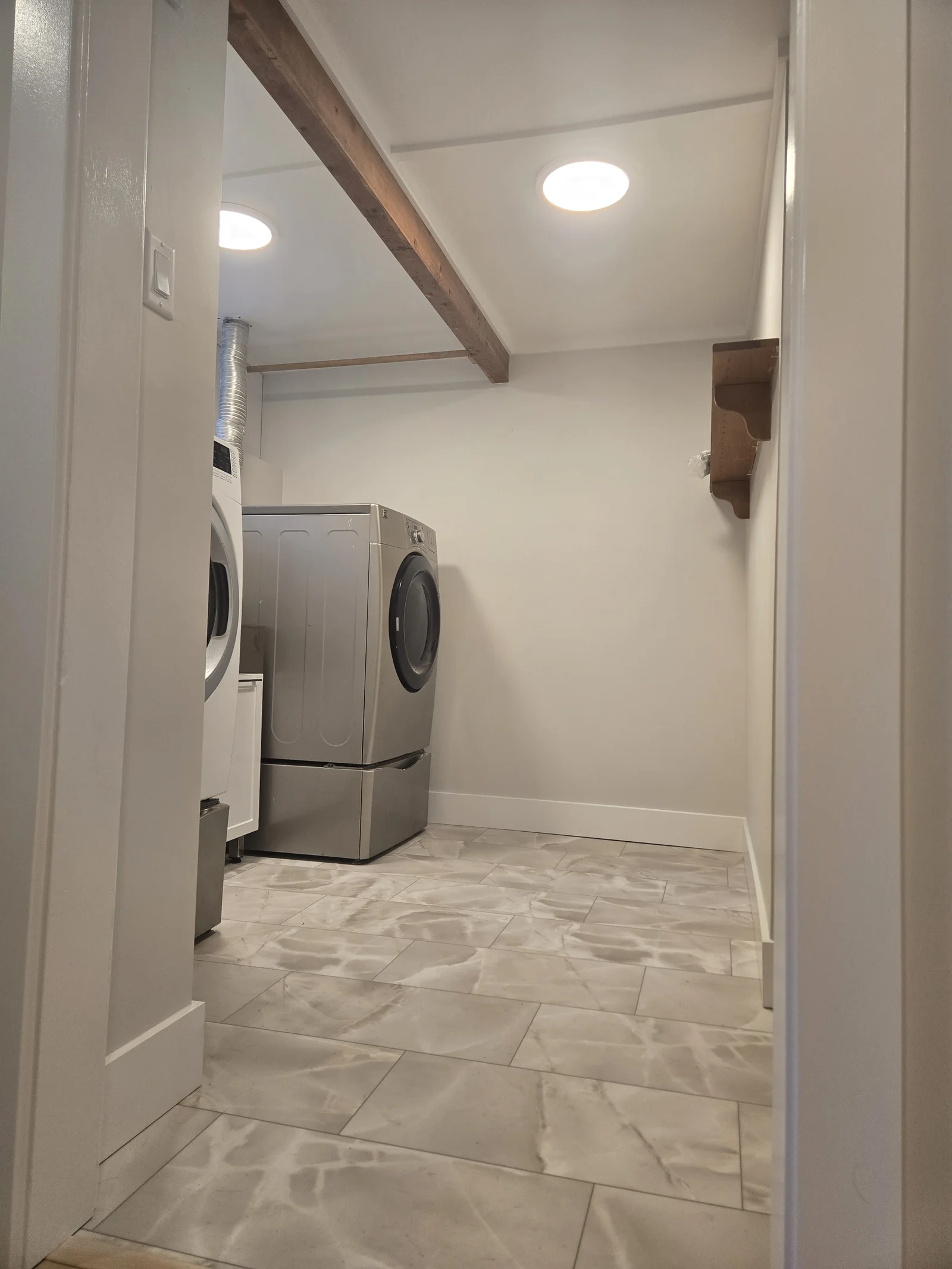 Laundry room with a finished ceiling, exposed wood beam and tiled floor
