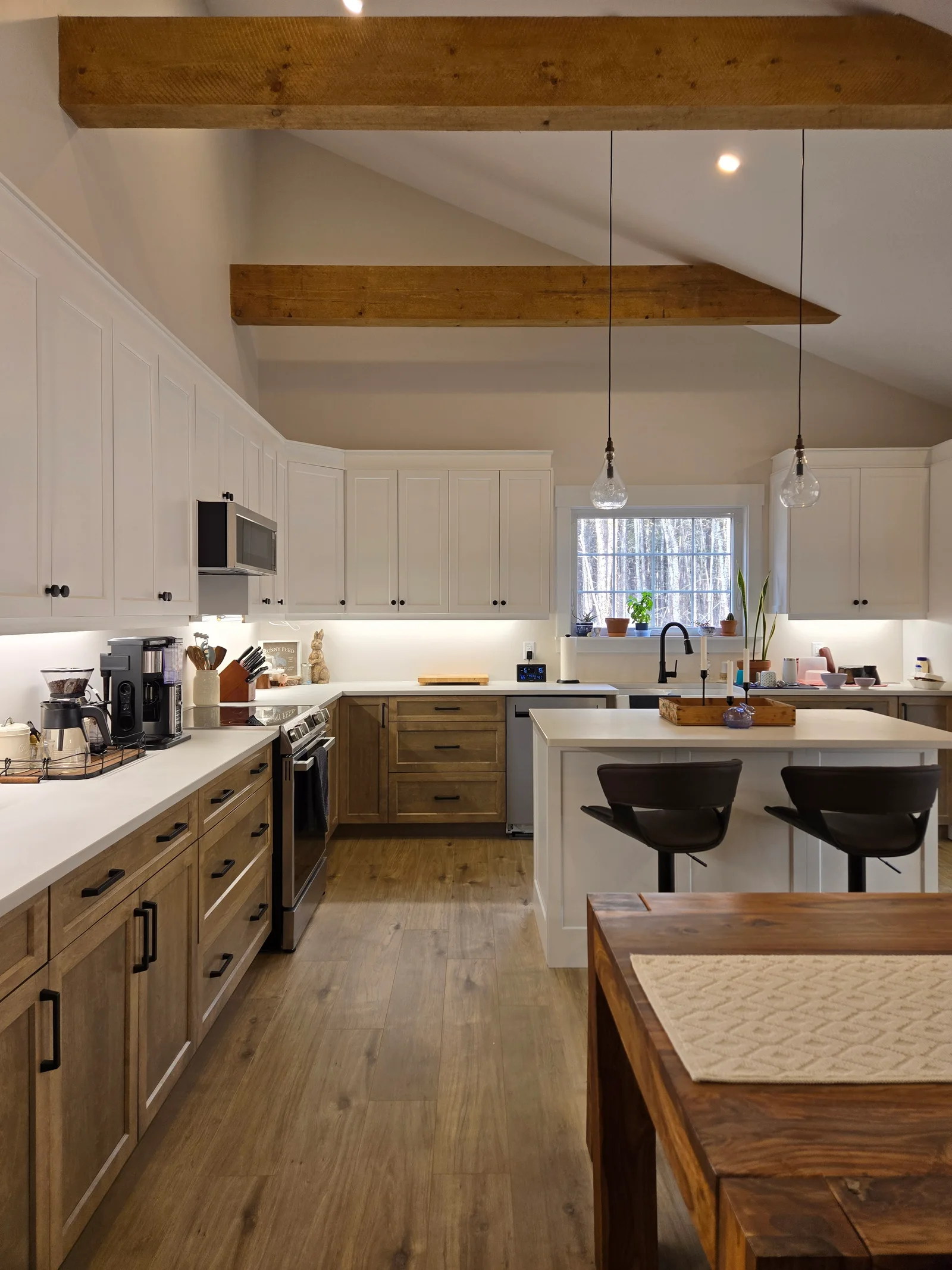 Kitchen with exposed timber beams, white upper cabinets and wood lower cabinets